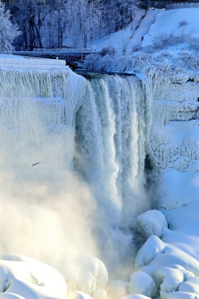 Bridal Veil Falls in wintertime with flowing water and snow and ice surrounding the waterfall.