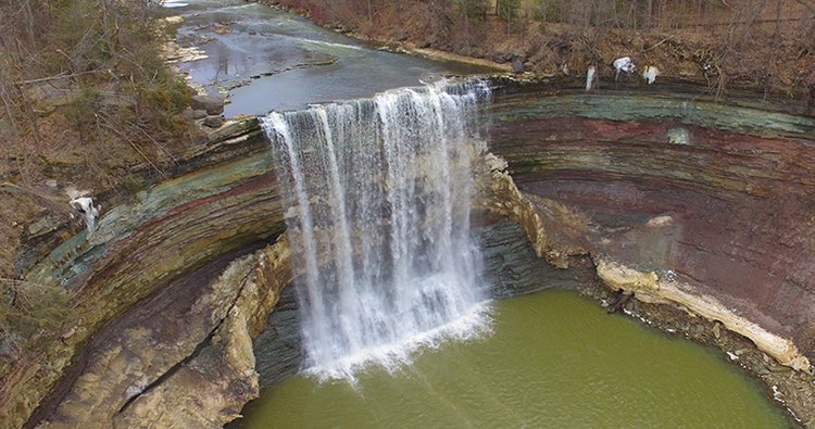 Aerial photo of Twenty Mile Waterfall with exposed rock units in a semicircular shape behind the falls. 
