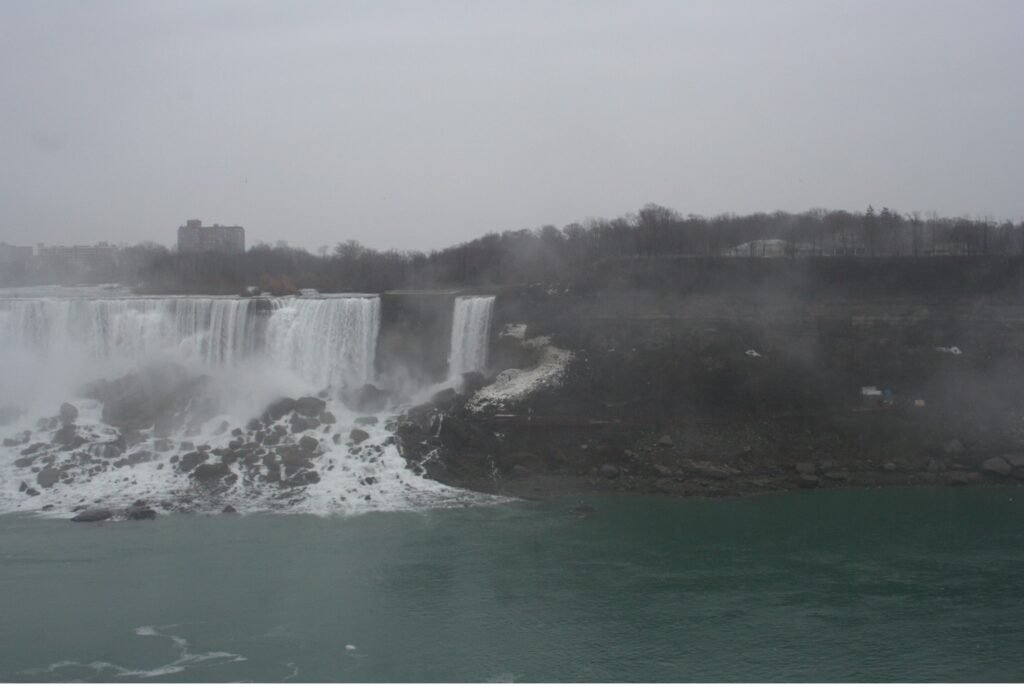 Niagara Falls from the Northern shore (Canadian side). There is fog in the air and the scene is partially obscured. 