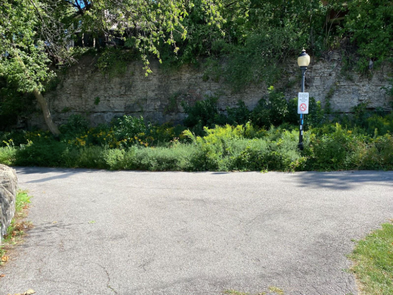 Pedestrian walkway with a lamppost and a cliffside in the background.