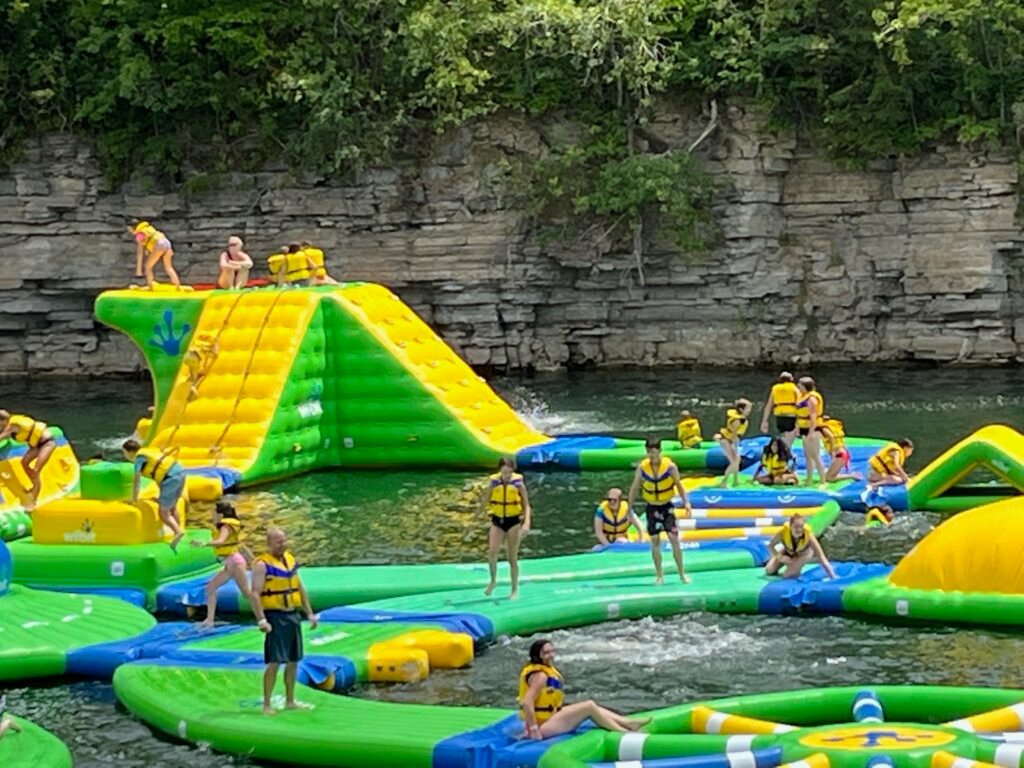 A bunch of people climb and play on a large inflatable waterpark