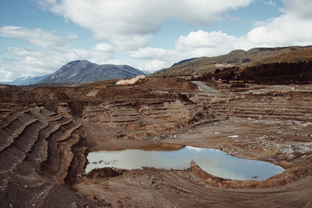 Open pit mine with water at the bottom and mountains in the background