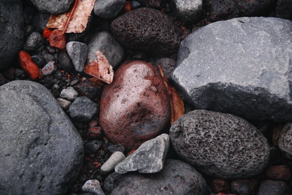 Close up photo of a bunch of grey rocks with one red rock in the middle.