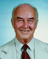 Headshot of a man in a lab coat and tie smiling at the camera.