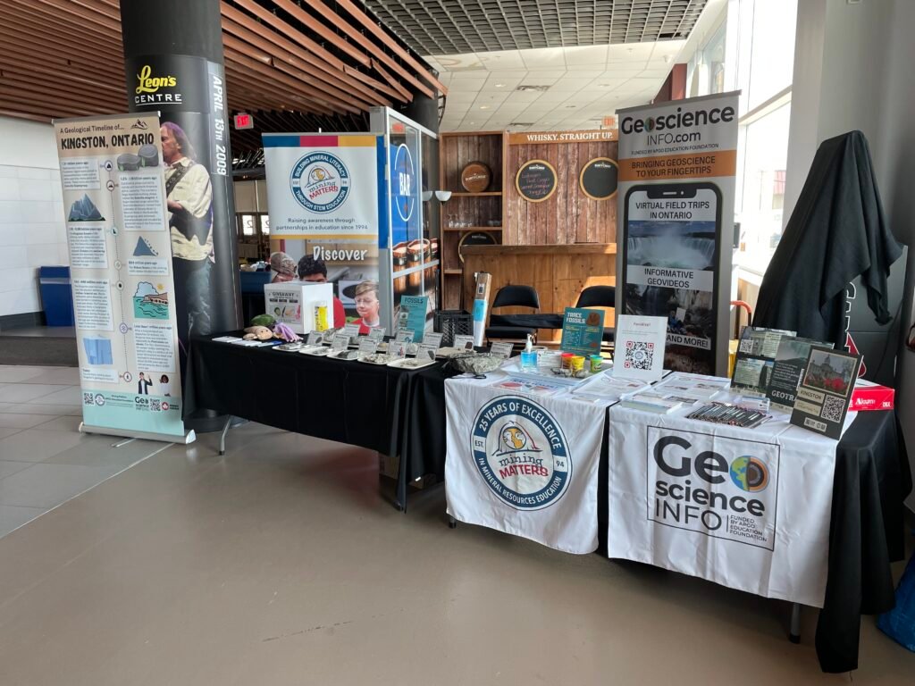 APGOEF's booth at Science Rendezvous. Two tables with black tablecloths and fossils on them. Beside the tables are standing banners with logos and information.