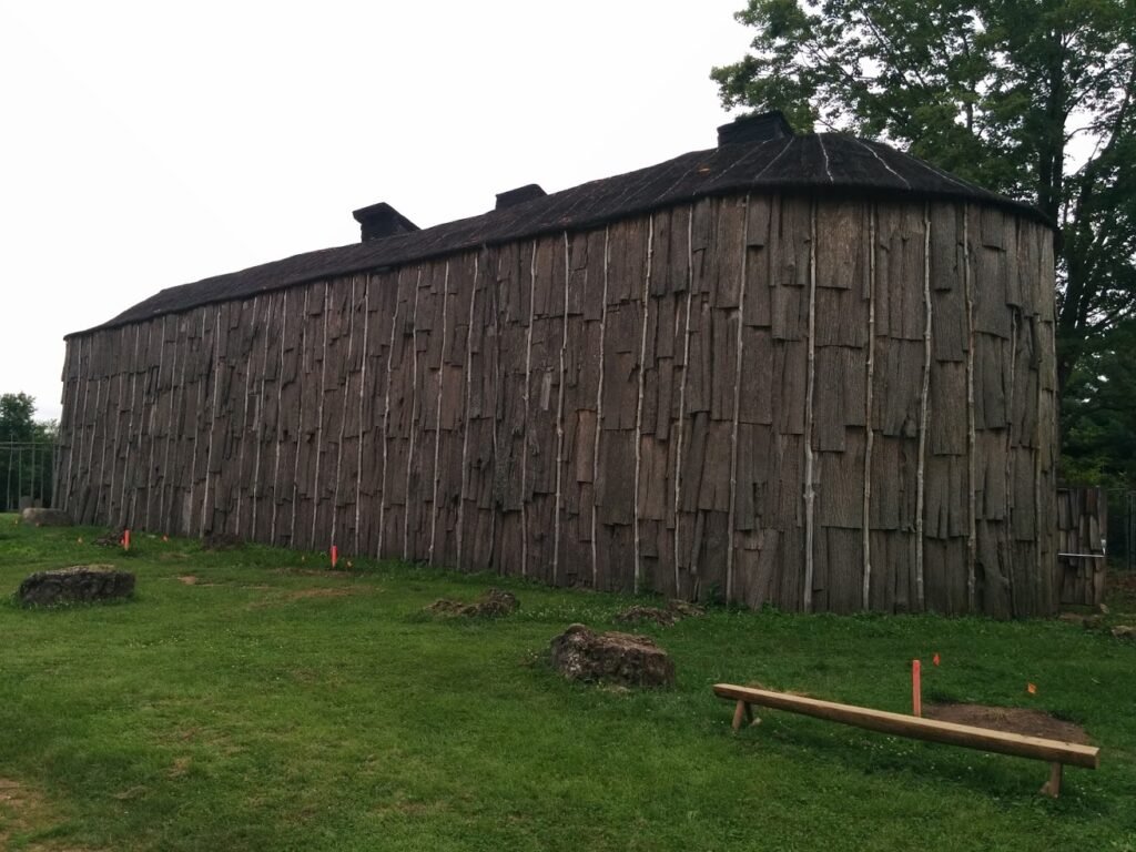 A reconstructed Iroquoian longhouse. The longhouse looks like a large elongated building with many wooden panels making up the walls.